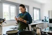 Seorang wanita tengah berinteraksi dengan perangkat rumah pintar, menunjukkan integrasi teknologi yang mulus dalam aktivitas sehari-hari di dalam rumah modern. Gambar ini merefleksikan kenyamanan dan efisiensi yang ditawarkan oleh perangkat cerdas masa kini.