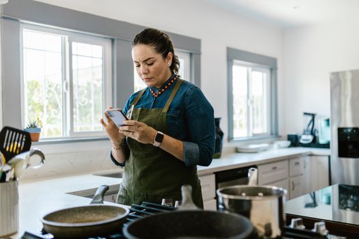 Seorang wanita tengah berinteraksi dengan perangkat rumah pintar, menunjukkan integrasi teknologi yang mulus dalam aktivitas sehari-hari di dalam rumah modern. Gambar ini merefleksikan kenyamanan dan efisiensi yang ditawarkan oleh perangkat cerdas masa kini.