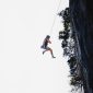 Seorang wanita terlihat tenang menghadapi terpaan angin kencang di puncak gunung, merepresentasikan ketangguhan mental yang diperlukan untuk menghadapi ketidakpastian hidup. Gambar ini menunjukkan bahwa dengan pola pikir yang tepat, setiap individu mampu menghadapi tantangan dengan ketenangan dan kekuatan batin.