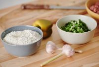 Wanita sedang menyiapkan bahan-bahan segar seperti sayuran dan buah-buahan di dapur yang bersih, menunjukkan proses awal untuk membuat hidangan sehat dan lezat di rumah. Pemandangan ini menginspirasi untuk memulai kebiasaan memasak sehat demi gaya hidup yang lebih baik.