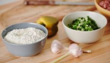Wanita sedang menyiapkan bahan-bahan segar seperti sayuran dan buah-buahan di dapur yang bersih, menunjukkan proses awal untuk membuat hidangan sehat dan lezat di rumah. Pemandangan ini menginspirasi untuk memulai kebiasaan memasak sehat demi gaya hidup yang lebih baik.