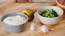 Wanita sedang menyiapkan bahan-bahan segar seperti sayuran dan buah-buahan di dapur yang bersih, menunjukkan proses awal untuk membuat hidangan sehat dan lezat di rumah. Pemandangan ini menginspirasi untuk memulai kebiasaan memasak sehat demi gaya hidup yang lebih baik.