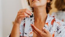 Seorang wanita tengah mengaplikasikan serum wajah di depan cermin, menggambarkan komitmen terhadap rutinitas perawatan kulit harian. Ini merupakan representasi visual dari dedikasi terhadap kesehatan kulit yang memancarkan kilau alami, melampaui sekadar produk kosmetik.