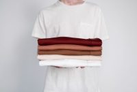 Seorang wanita mengenakan busana bergaya minimalis dengan siluet bersih dan warna netral yang elegan, dipadukan dengan aksesori yang menampilkan sentuhan etnik Indonesia yang kaya, mencerminkan tren fashion terkini. Pakaian ini menonjolkan perpaduan harmonis antara kesederhanaan modern dan kekayaan budaya lokal yang kini mendunia.
