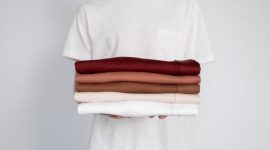 Seorang wanita mengenakan busana bergaya minimalis dengan siluet bersih dan warna netral yang elegan, dipadukan dengan aksesori yang menampilkan sentuhan etnik Indonesia yang kaya, mencerminkan tren fashion terkini. Pakaian ini menonjolkan perpaduan harmonis antara kesederhanaan modern dan kekayaan budaya lokal yang kini mendunia.