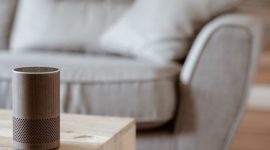 Ruang keluarga modern yang futuristis menunjukkan berbagai perangkat pintar seperti layar sentuh kendali dan pencahayaan otomatis, merefleksikan integrasi teknologi dalam gaya hidup sehari-hari. Desain minimalis ini menggambarkan kenyamanan dan efisiensi yang ditawarkan oleh ekosistem rumah pintar.
