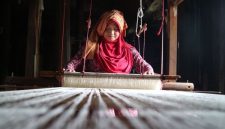 Model mengenakan busana yang memadukan tenun ikat tradisional Indonesia dengan desain kontemporer, merefleksikan tren mode 2026 yang mengedepankan keberlanjutan dan identitas lokal. Pilihan material ramah lingkungan dan sentuhan estetika retro menambah dimensi baru pada koleksi yang relevan untuk gaya hidup modern.