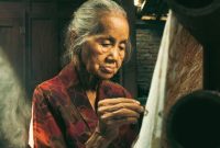 Seorang wanita mengenakan kain batik sedang menata dagangan rempah di pasar tradisional, mencerminkan kekayaan budaya dan gaya hidup lokal Indonesia yang masih sangat kental dengan nuansa tradisional. Pemandangan ini menunjukkan betapa kuatnya akar budaya dalam kehidupan sehari-hari masyarakat kita.