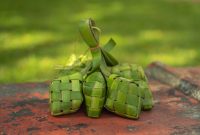 Tumpukan ketupat segar yang baru matang, siap disajikan dengan berbagai hidangan Lebaran. Anyaman janur yang rapi melambangkan kesucian dan tradisi yang telah diwariskan turun-temurun di Indonesia.