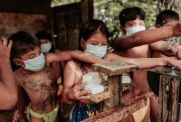 Seorang anak di pedesaan Kalimantan Selatan sedang minum air bersih dari keran umum, yang menunjukkan pentingnya akses terhadap sumber air minum layak untuk mencegah masalah kesehatan seperti stunting. Upaya pemerintah dan komunitas terus digalakkan untuk memastikan setiap keluarga mendapatkan akses sanitasi dan air bersih yang memadai.