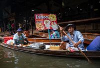 Pemandangan hidup pasar terapung di Kalimantan, di mana perahu-perahu tradisional dipenuhi hasil bumi segar berinteraksi dengan pembeli di tengah aliran sungai. Ini adalah cerminan otentik dari kehidupan sehari-hari dan warisan budaya yang tak ternilai harganya.