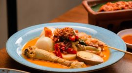 Semangkuk Soto Banjar hangat dengan irisan ayam, telur rebus, dan perkedel kentang, siap memanjakan lidah dengan kekayaan rempahnya yang otentik. Hidangan khas Kalimantan Selatan ini memancarkan kehangatan dan cita rasa Nusantara yang tak terlupakan.