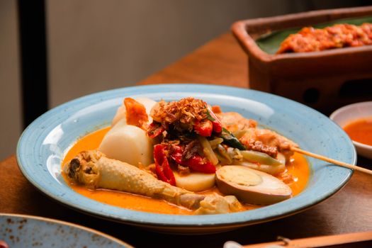 Semangkuk Soto Banjar hangat dengan irisan ayam, telur rebus, dan perkedel kentang, siap memanjakan lidah dengan kekayaan rempahnya yang otentik. Hidangan khas Kalimantan Selatan ini memancarkan kehangatan dan cita rasa Nusantara yang tak terlupakan.