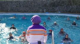 Sekelompok wanita dengan semangat melakukan gerakan Senam Baiman di ruang terbuka, menunjukkan perpaduan harmonis antara kebugaran fisik dan ekspresi budaya tradisional Banjar. Senam ini menjadi cara menyenangkan untuk menjaga kesehatan sekaligus melestarikan warisan seni tari lokal.