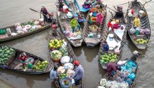 Para pedagang lokal sibuk menjajakan dagangan mereka dari atas perahu tradisional, menciptakan pemandangan khas pasar terapung yang ramai dan penuh warna di pagi hari. Aktivitas ini menunjukkan interaksi sosial dan ekonomi yang telah menjadi bagian integral dari kehidupan masyarakat setempat selama berabad-abad.