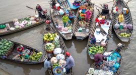 Para pedagang lokal sibuk menjajakan dagangan mereka dari atas perahu tradisional, menciptakan pemandangan khas pasar terapung yang ramai dan penuh warna di pagi hari. Aktivitas ini menunjukkan interaksi sosial dan ekonomi yang telah menjadi bagian integral dari kehidupan masyarakat setempat selama berabad-abad.