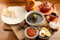 Semangkuk soto Banjar hangat lengkap dengan potongan lontong, telur rebus, dan taburan bawang goreng, siap memanjakan lidah dengan kekayaan rempah khas Kalimantan. Hidangan ini menjadi daya tarik utama kuliner di Banjarmasin.