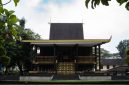 Patung Sultan Suriansyah berdiri gagah di Banjarmasin, mengenang pendiri Kesultanan Banjar yang mengubah arah sejarah wilayah ini dengan memeluk agama Islam. Terlihat pula latar belakang arsitektur tradisional Banjar yang mencerminkan kekayaan budaya yang telah diwariskan.