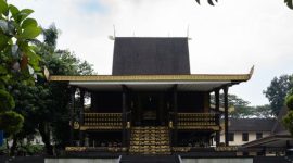 Patung Sultan Suriansyah berdiri gagah di Banjarmasin, mengenang pendiri Kesultanan Banjar yang mengubah arah sejarah wilayah ini dengan memeluk agama Islam. Terlihat pula latar belakang arsitektur tradisional Banjar yang mencerminkan kekayaan budaya yang telah diwariskan.