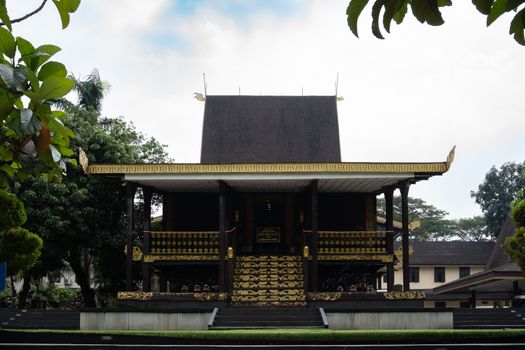 Patung Sultan Suriansyah berdiri gagah di Banjarmasin, mengenang pendiri Kesultanan Banjar yang mengubah arah sejarah wilayah ini dengan memeluk agama Islam. Terlihat pula latar belakang arsitektur tradisional Banjar yang mencerminkan kekayaan budaya yang telah diwariskan.