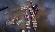 Pemandangan udara Sungai Barito yang membelah lanskap hijau Kalimantan, menunjukkan keindahan alami dan vitalitasnya sebagai jalur kehidupan utama bagi masyarakat di sekitarnya. Perahu-perahu tradisional terlihat berlayar tenang, menggambarkan harmoni antara manusia dan alam di tepian sungai yang megah ini.