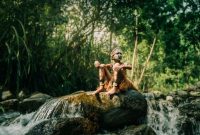 Seorang perempuan Suku Dayak Meratus dengan pakaian tradisionalnya, menyatu harmonis dengan rimbunnya hutan Kalimantan. Pakaian ini mencerminkan kekayaan budaya dan kedekatan mereka dengan alam yang menjadi sumber kehidupan.
