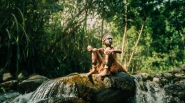 Seorang perempuan Suku Dayak Meratus dengan pakaian tradisionalnya, menyatu harmonis dengan rimbunnya hutan Kalimantan. Pakaian ini mencerminkan kekayaan budaya dan kedekatan mereka dengan alam yang menjadi sumber kehidupan.