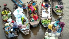 Pemandangan pasar terapung yang hidup di Kalimantan, menampilkan para pedagang berinteraksi dari atas jukung mereka yang penuh dengan aneka hasil bumi segar, sebuah tradisi yang terus lestari.