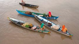 Suasana pagi hari yang semarak di salah satu pasar terapung Indonesia, menampilkan perahu-perahu tradisional yang sarat dengan aneka hasil bumi dan kuliner, siap melayani para pembeli. Interaksi unik ini menggambarkan kekayaan budaya dan kearifan lokal masyarakat sungai.