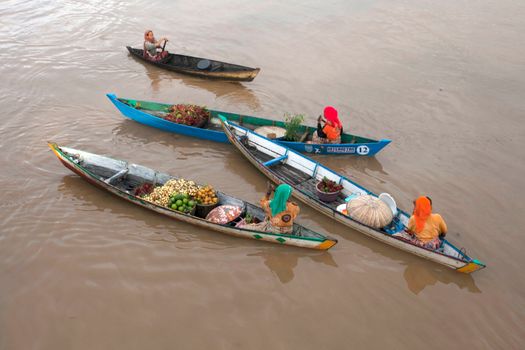 Suasana pagi hari yang semarak di salah satu pasar terapung Indonesia, menampilkan perahu-perahu tradisional yang sarat dengan aneka hasil bumi dan kuliner, siap melayani para pembeli. Interaksi unik ini menggambarkan kekayaan budaya dan kearifan lokal masyarakat sungai.