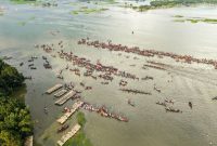 Pemandangan udara Sungai Barito dengan perahu-perahu tradisional yang melintas, menunjukkan peran vitalnya sebagai jalur transportasi dan denyut nadi kehidupan masyarakat Kalimantan.