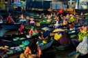 Deretan perahu jukung berisi beragam dagangan segar mengapung di sungai, menyajikan pemandangan khas pasar terapung di Kalimantan yang ramai dengan aktivitas jual beli. Para pedagang dengan cekatan melayani pembeli, menciptakan suasana interaksi yang hidup dan penuh warna di atas air.