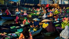 Deretan perahu jukung berisi beragam dagangan segar mengapung di sungai, menyajikan pemandangan khas pasar terapung di Kalimantan yang ramai dengan aktivitas jual beli. Para pedagang dengan cekatan melayani pembeli, menciptakan suasana interaksi yang hidup dan penuh warna di atas air.